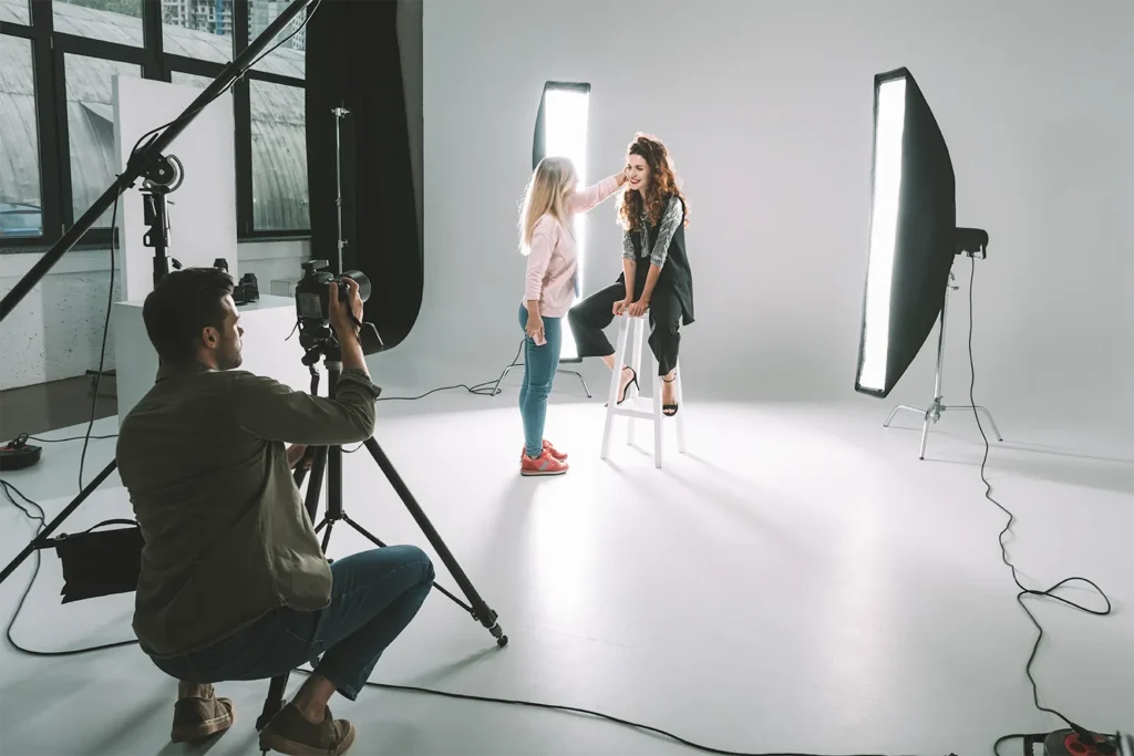 A professional photographer gets ready to shoot a photo as a makeup artist preps the talent